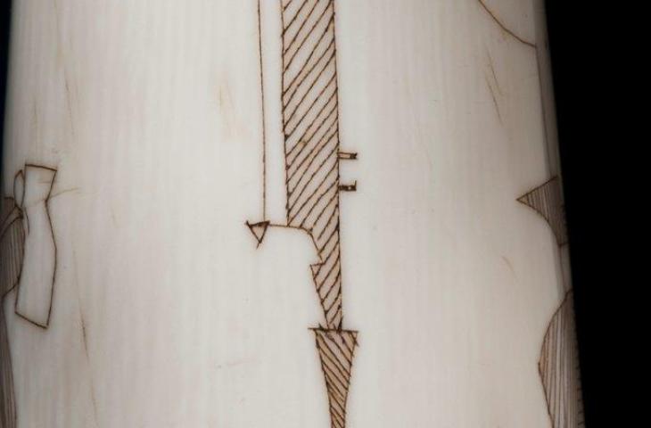 Detail of horn 1983.033: an adze and a knife engraved on the bell of the horn